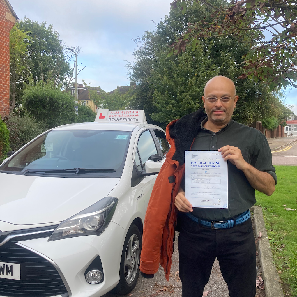 Driving pupil holding a pass certificate next to the Pass with Ash learner car.