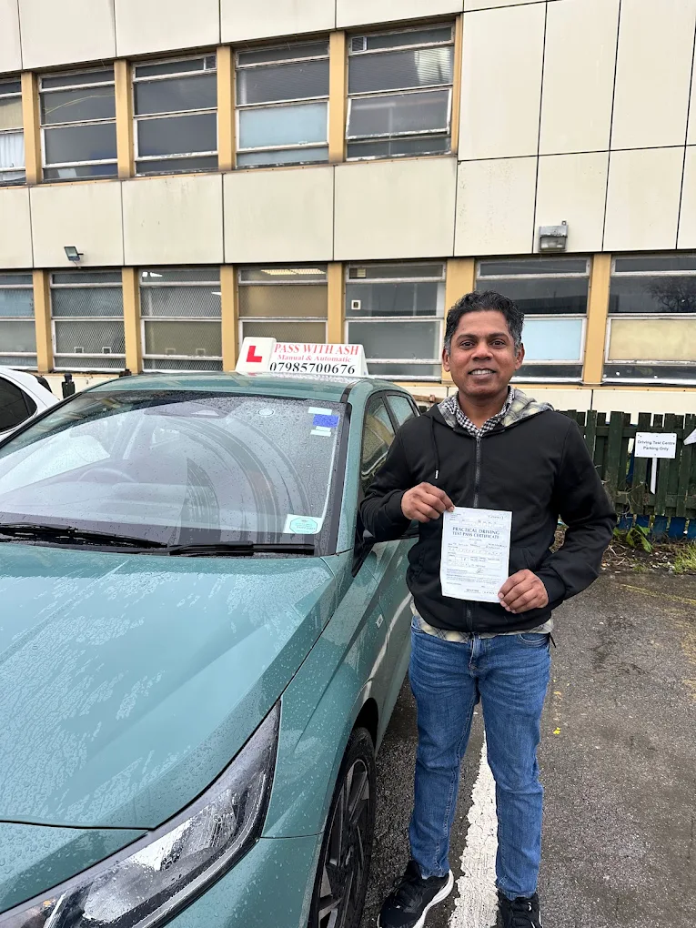 Successful learner driver holding a pass certificate beside the Pass with Ash car.