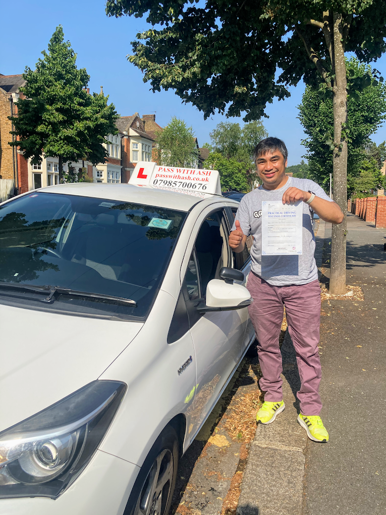 Successful driving pupil giving a thumbs up beside the Pass with Ash learner vehicle.